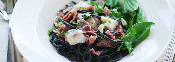 Czarny makaron z żabnicą, szynką parmeńską i szczawiem