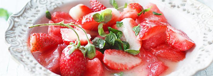 Dessert salad with watermelon and strawberries in white chocolate and mint sauce