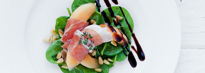 Salad with melon in prosciutto on spinach