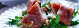 Świeże figi w szynce parmeńskiej na rukoli